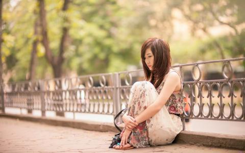 悲伤的亚洲女孩，坐在街头壁纸