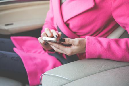 恰好打扮的女人在汽车中使用她的手机