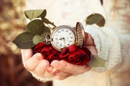 一个女孩的手，一个时钟，猩红色的玫瑰