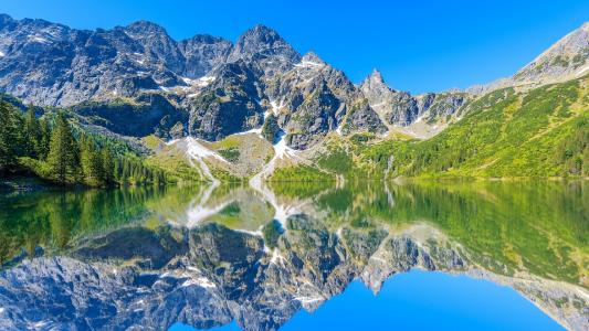 阿尔卑斯山，湖面光滑，绿树环绕，倒影