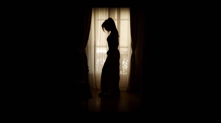 打扮的女人站在窗口附近的剪影高清壁纸