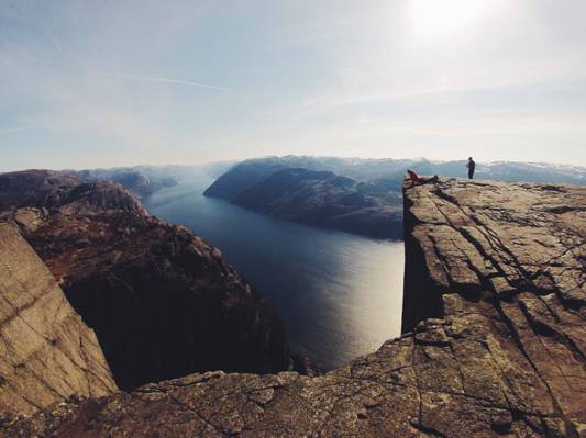 人站在悬崖的边缘,俯瞰山环绕的高清壁纸