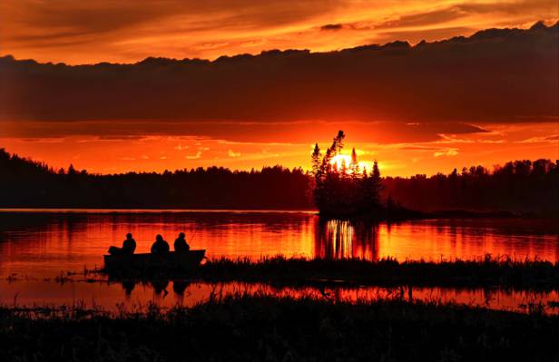 剪影照片的3人骑在鱼船上近期的草在太阳落山高清壁纸