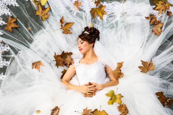 妇女的白色蕾丝婚纱靠在地面与枫叶高清壁纸