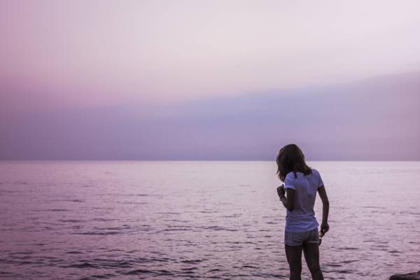 白色t恤和站在海滩旁边的蓝色短裤的女人高清壁纸