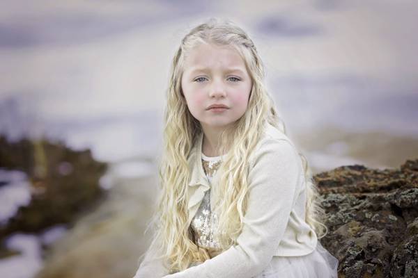 女孩穿着白色的羊毛衫,坐在棕色的岩石高清壁纸
