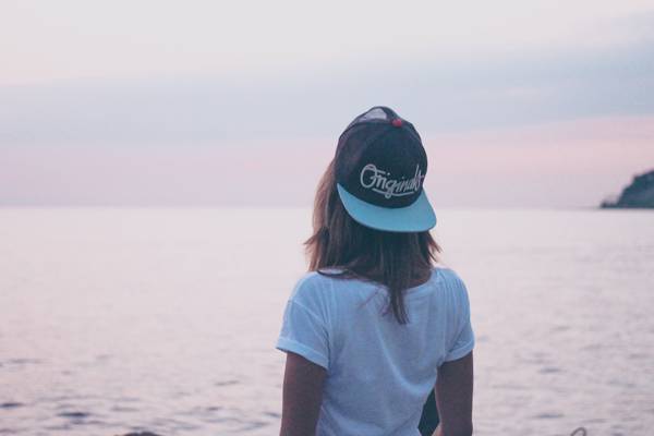 女人在白色汤匙领T恤和黑与蓝绿色装白色边缘帽服装站在海边白天高清壁纸