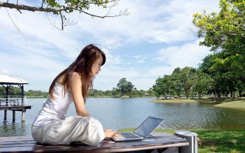 一台笔记本电脑在湖边的女孩