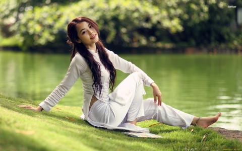穿白色西装的日本女孩坐在池塘的岸边