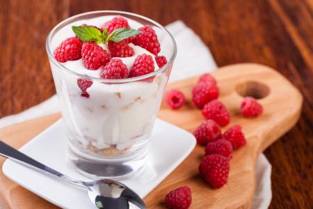 与酸奶和新鲜树莓在桌子上的玻璃甜点