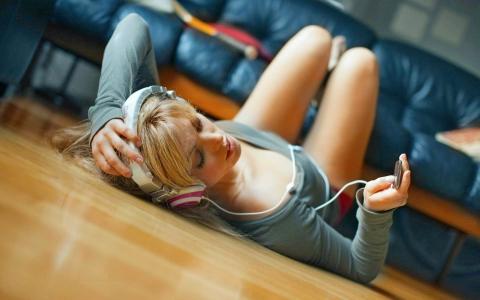 这个女孩躺在地上，用耳机听音乐