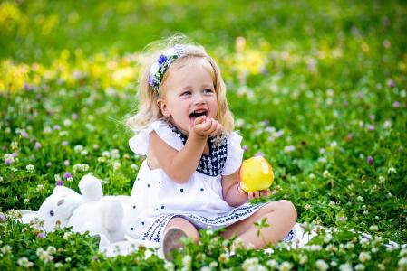 小女孩微笑着坐在绿草地上的苹果