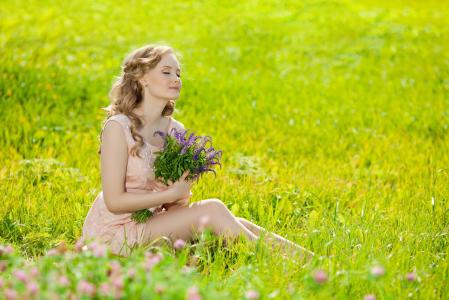 坐在绿草地上的花束的女孩