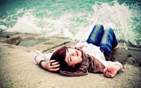 牛仔裤的赤脚女孩躺在江边