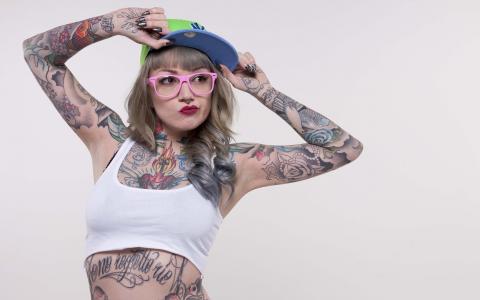 一顶帽子和粉红色眼镜的纹身的女孩