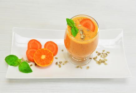 一杯胡萝卜鸡尾酒用在一个白色板材的桔子