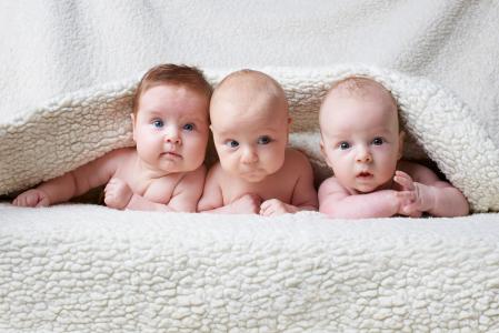 三个婴儿躺在毯子下面